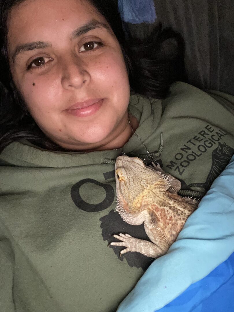 Person smiling with a bearded dragon on their chest.